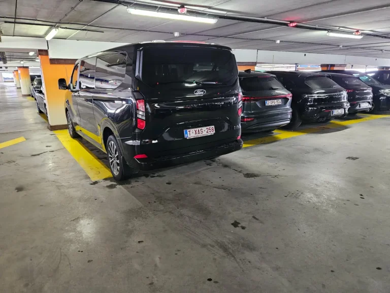 Black taxi van parked in a covered car park for an airport pick-up