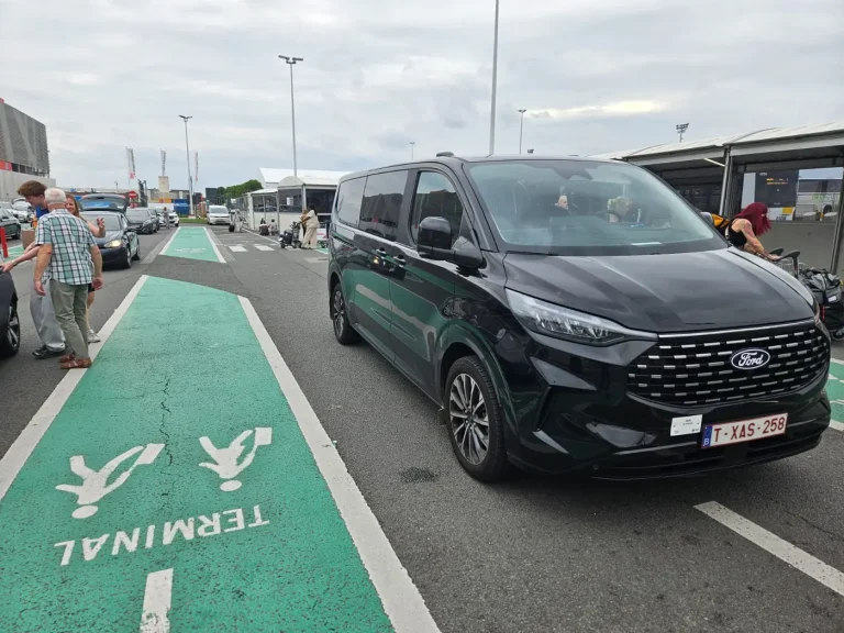Black Ford taxi van at the drop-off zone of a Belgian airport terminal